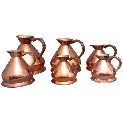 A set of six highly decorative 19th Century copper measuring jugs