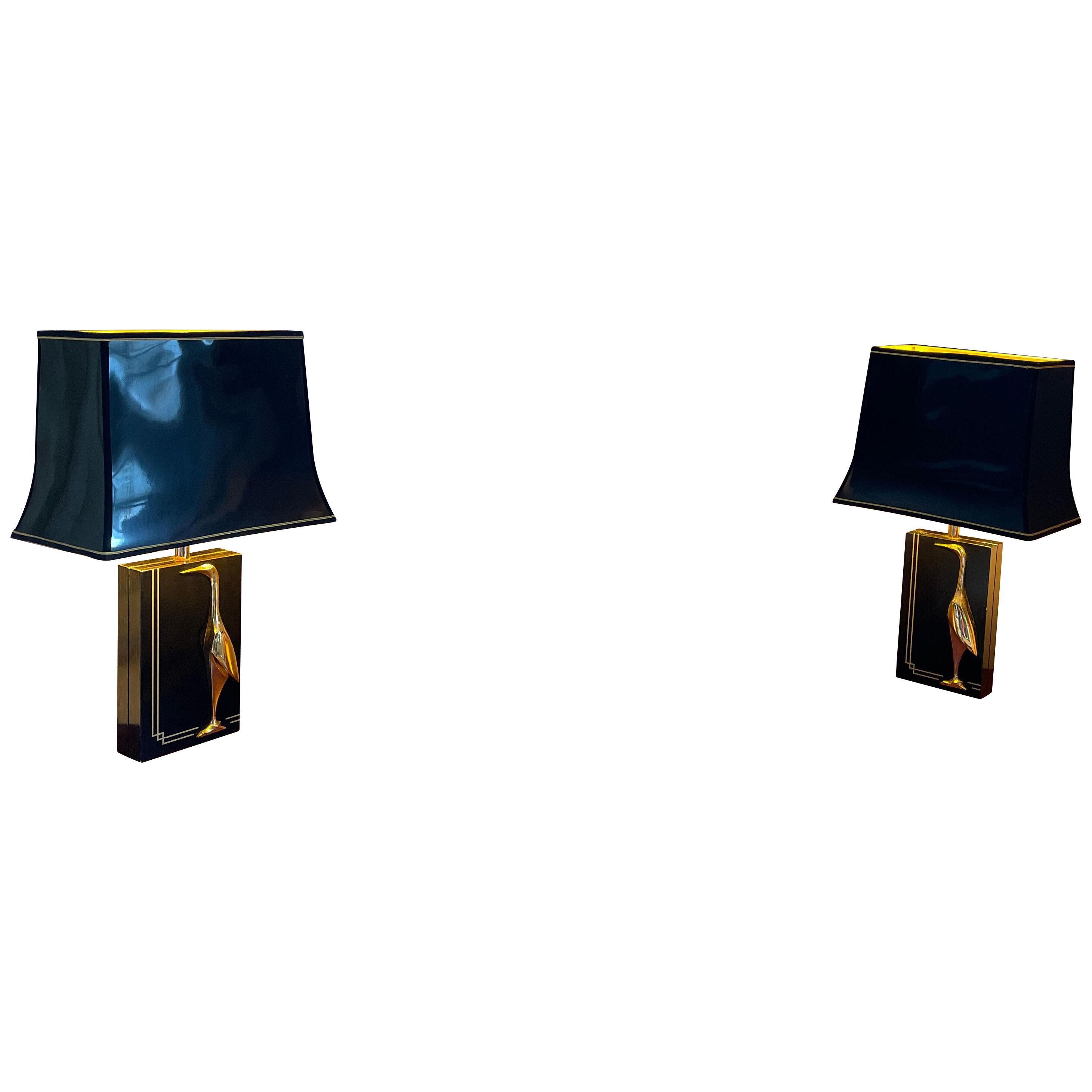 A pair of Hollywood Regency black wooden table lamps with brass bird decoration 