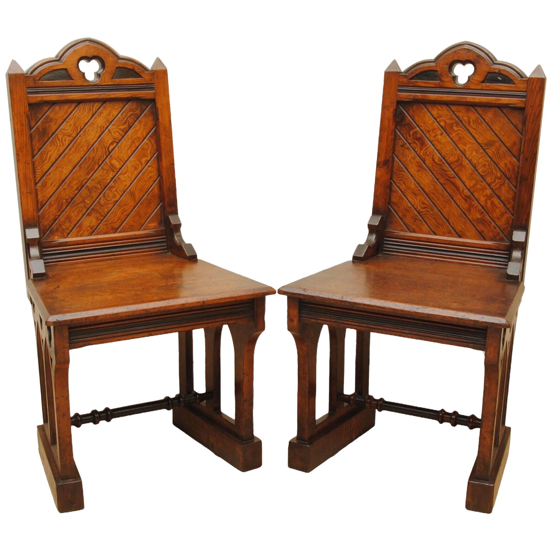 A PAIR OF 19TH CENTURY GOTHIC DESIGN PITCH PINE HALL CHAIRS